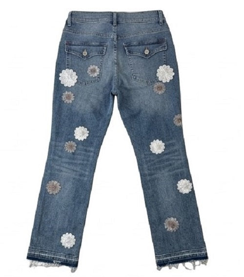 Blue jeans with floral patches on a white background