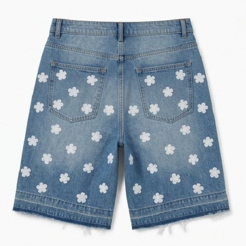 Blue denim shorts with white floral patterns on a white background