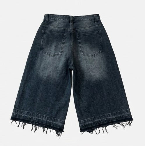 Back view of black denim shorts on a light gray background