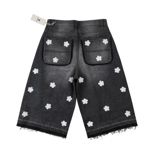 Black denim shorts with white floral patterns on a white background