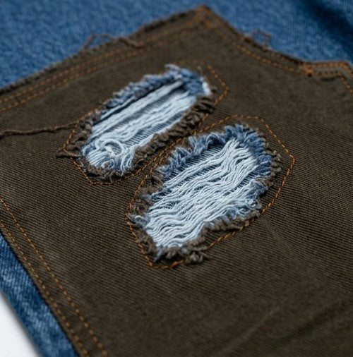 Close-up of a brown fabric patch with blue frayed edges on a denim background