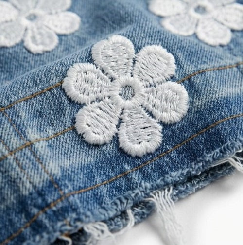 Close-up of denim fabric with white floral embroidery
