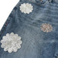 Close-up of blue denim shorts with floral lace patches.