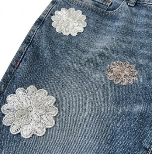 Close-up of blue denim shorts with floral lace patches.