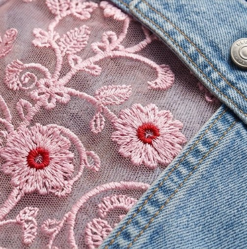Close-up of pink floral embroidery on a denim fabric background