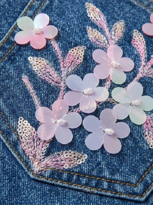 Embroidered floral design on denim fabric with pink and white flowers.
