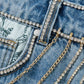Close-up of a denim jacket with decorative chains and rhinestones.