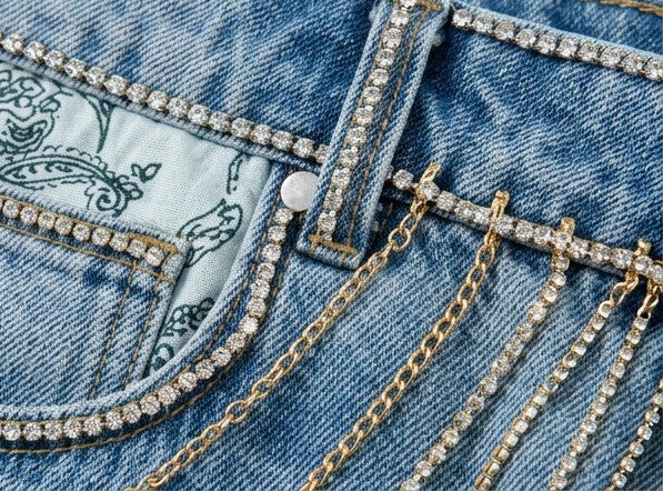 Close-up of a denim jacket with decorative chains and rhinestones.