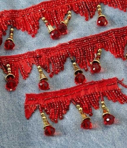Red beaded lace trim with gold accents on a denim background