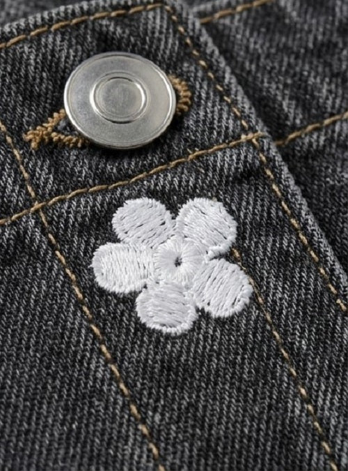 Close-up of a button and embroidered flower on denim fabric