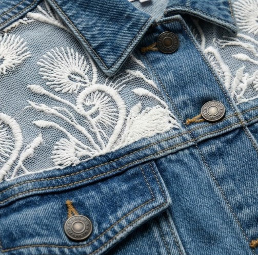 Close-up of a denim jacket with white floral embroidery