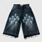 Black denim shorts with blue cross patterns on a white background