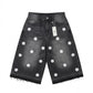 Black denim shorts with white floral patterns and a tag on a white background