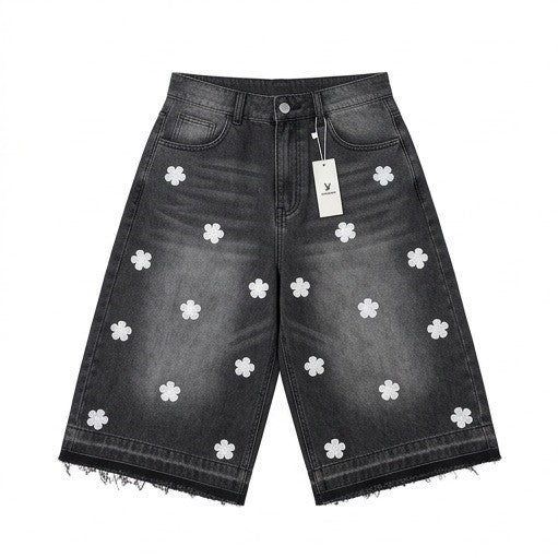 Black denim shorts with white floral patterns and a tag on a white background