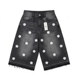 Black denim shorts with white floral patterns and a tag on a white background