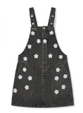 Black denim pinafore dress with white floral patterns on a white background