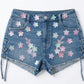 Denim shorts with floral patterns on a white background