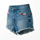 Blue denim shorts with colorful patch on a white background