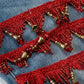Close-up of red embroidered fabric with gold beads on a blue denim background